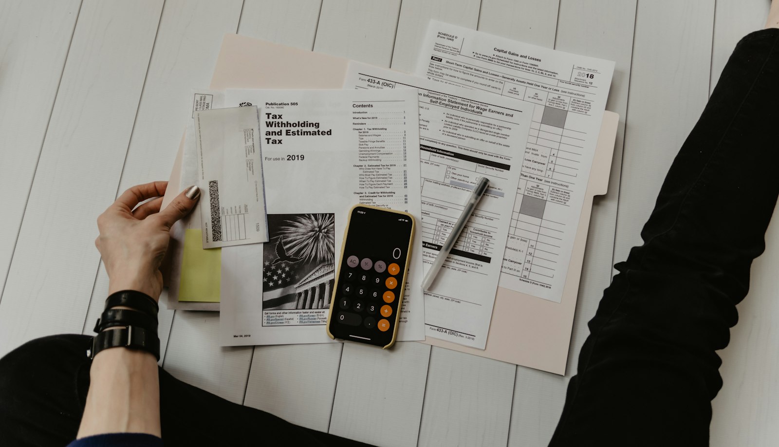Calculator, notebook and labelled budget envelopes on a clean desk — household cash-flow planning workspace